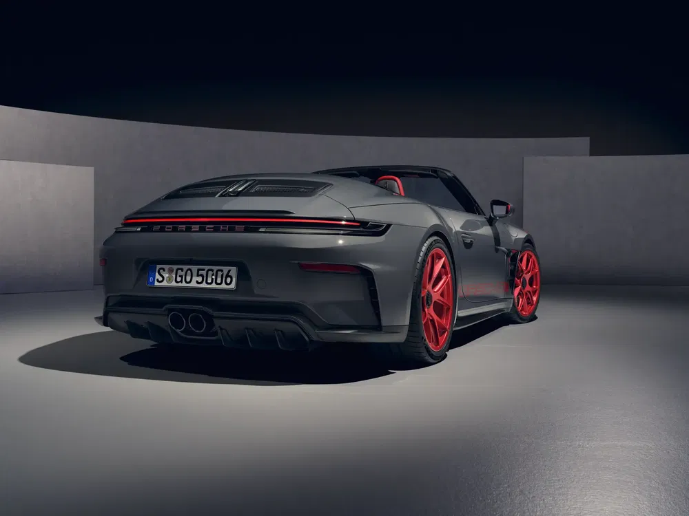 Porsche 911 grise avec jantes rouges distinctives dans un studio élégant.