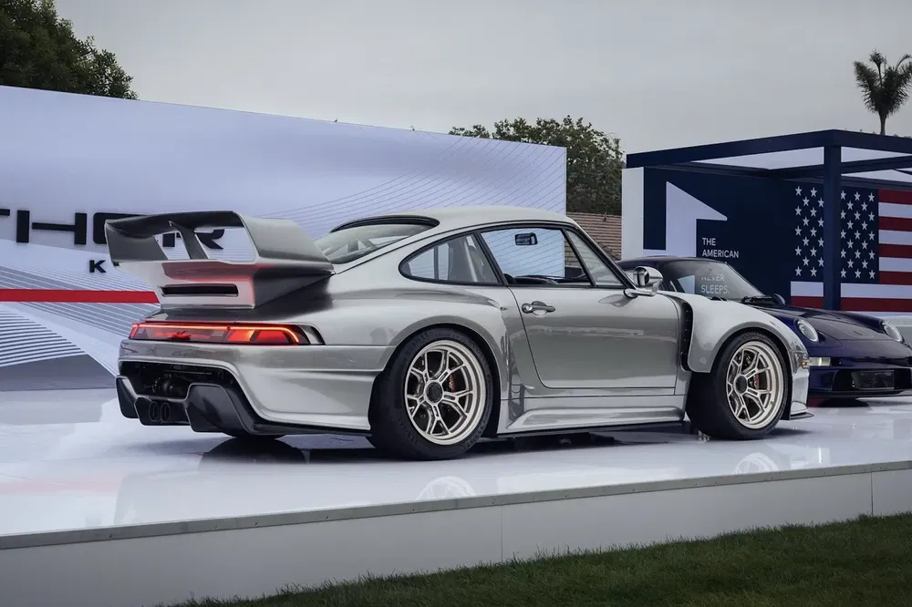 Zilveren Porsche sportwagen met achtervleugel tentoongesteld op buitententoonstelling.