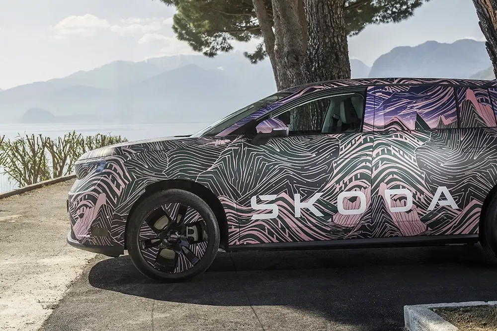 {"fr":"Prototype Skoda SUV camouflé avec design unique, stationné devant un paysage de lac serein.","nl":"Skoda SUV prototype met unieke camouflage, geparkeerd voor een rustige meeromgeving."}