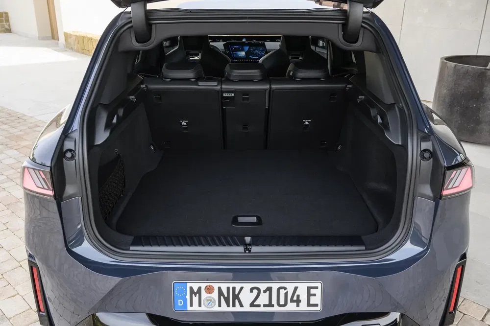 Coffre spacieux d'une BMW iX avec sièges arrière rabattables et intérieur moderne.