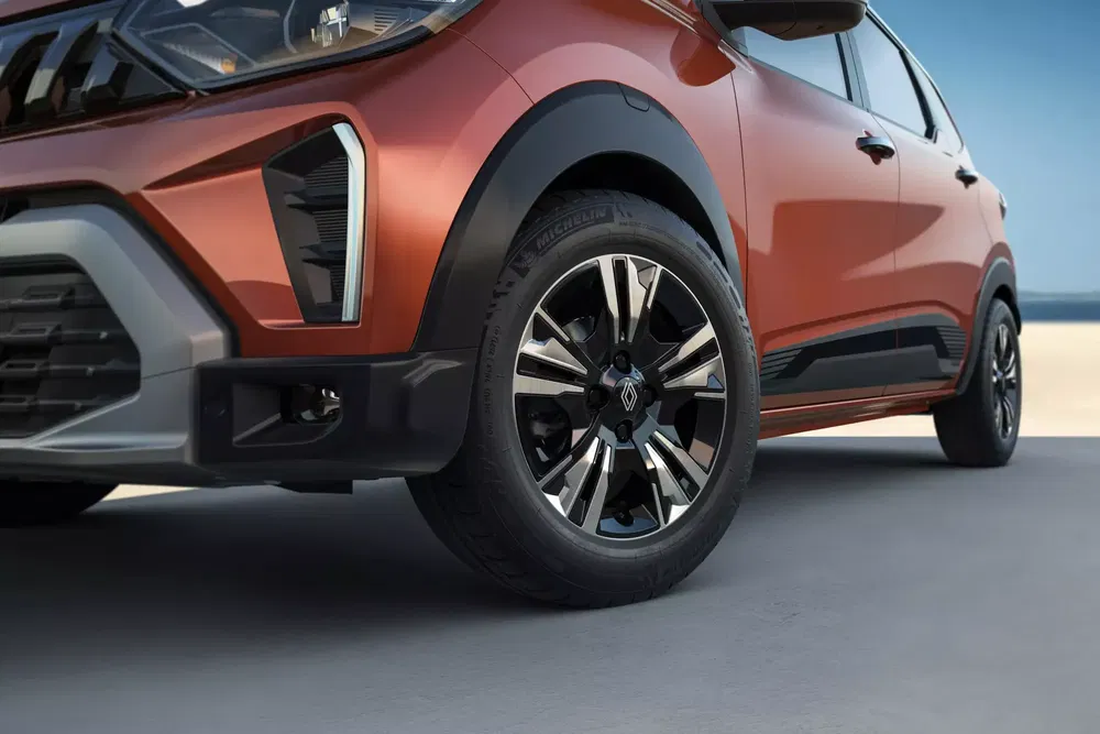 Vue rapprochée d'un SUV Renault Kiger rouge, roues avant sur fond de ciel bleu.