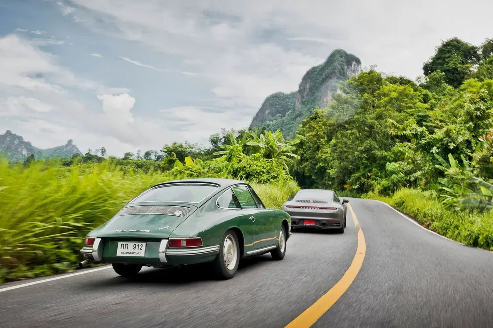 {"fr":"Deux Porsche classiques sur route sinueuse entourée de verdure et montagnes.","nl":"Twee klassieke Porsches op bochtige weg omgeven door groen en bergen."}