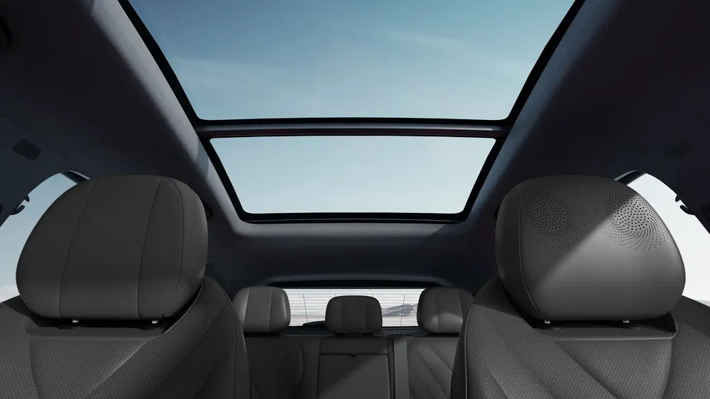 Interieur van de Volkswagen ID.4 met open panoramadak tegen een blauwe lucht.