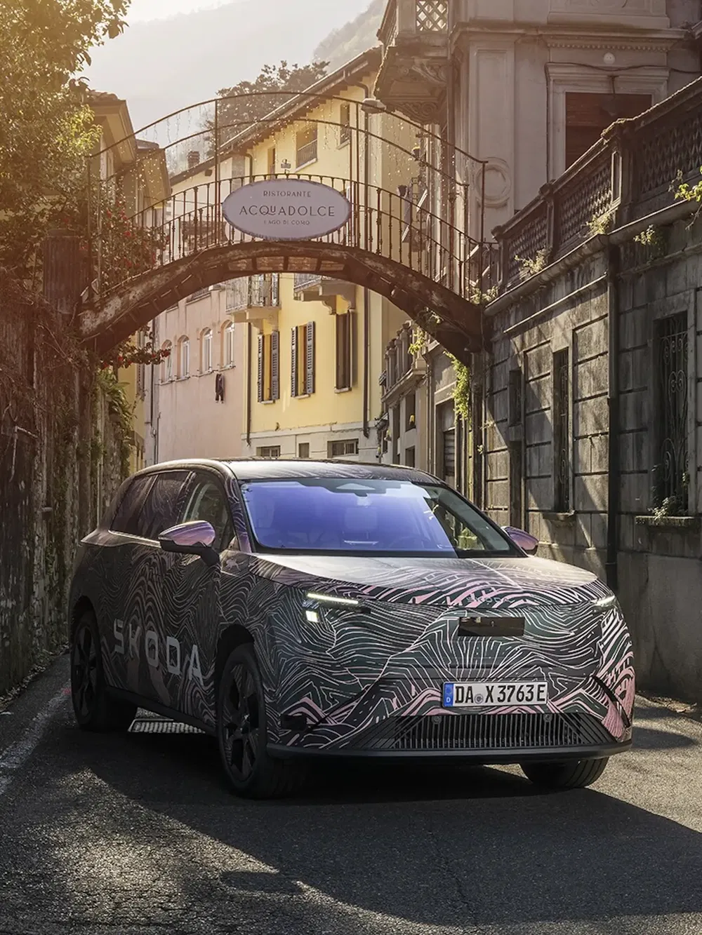 Gecamoufleerde Skoda SUV in een schilderachtige straat van een Europees dorp.