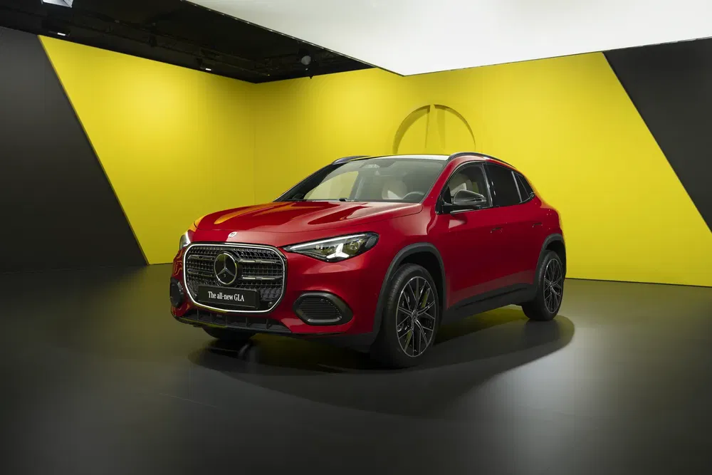 Nouveau Mercedes-Benz GLA rouge sur fond jaune vif au salon automobile.