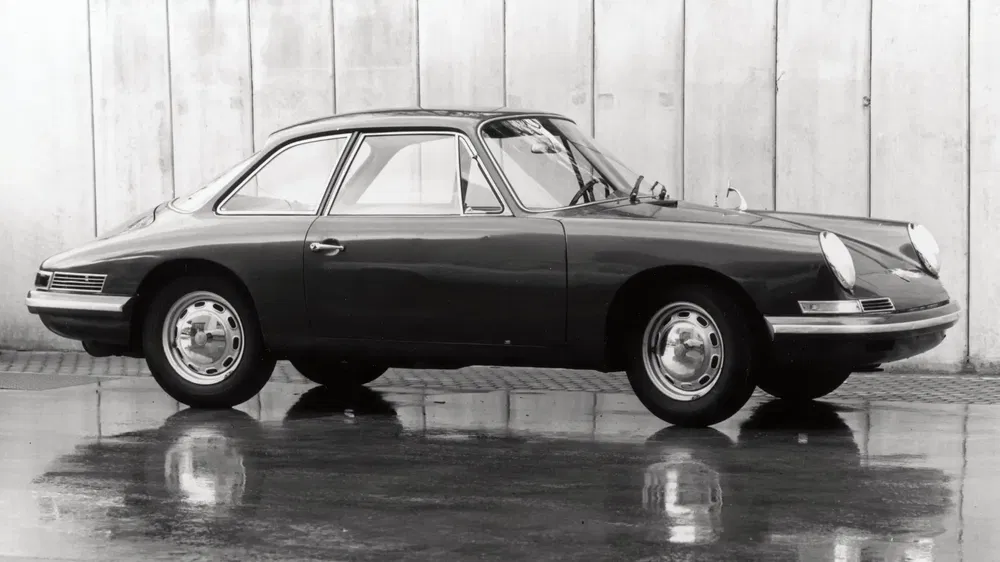 Porsche 911 vintage zijaanzicht tegen betonachtergrond, iconische sportwagen uit de jaren '60.