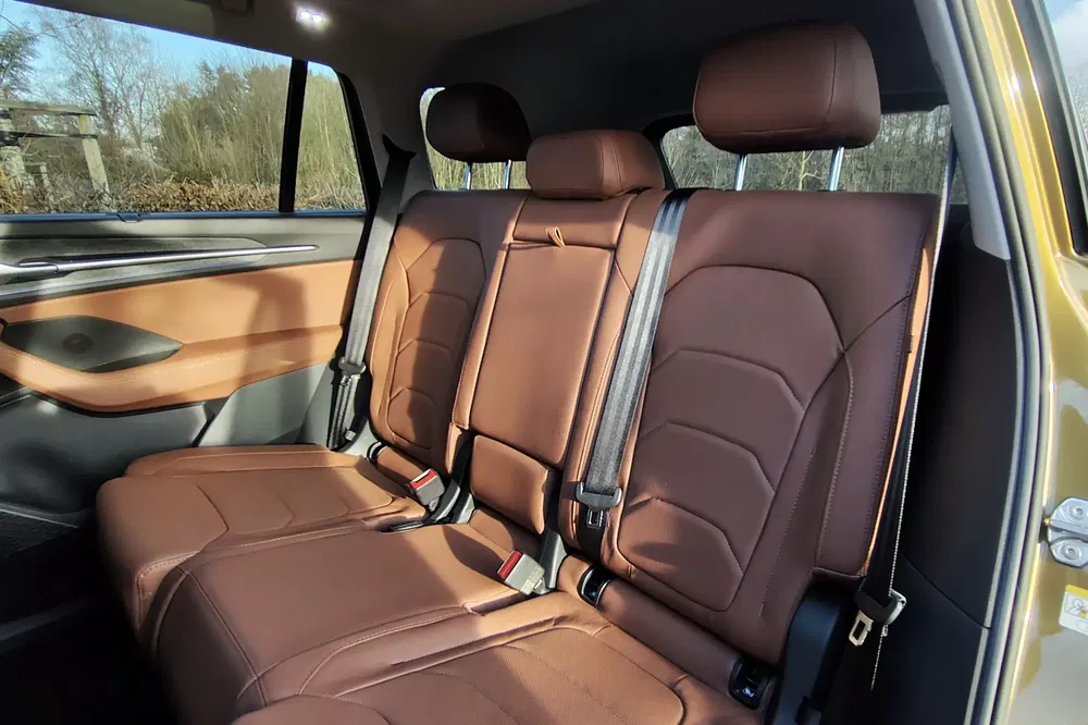 Intérieur de voiture avec sièges en cuir marron, vue arrière spacieuse et moderne.