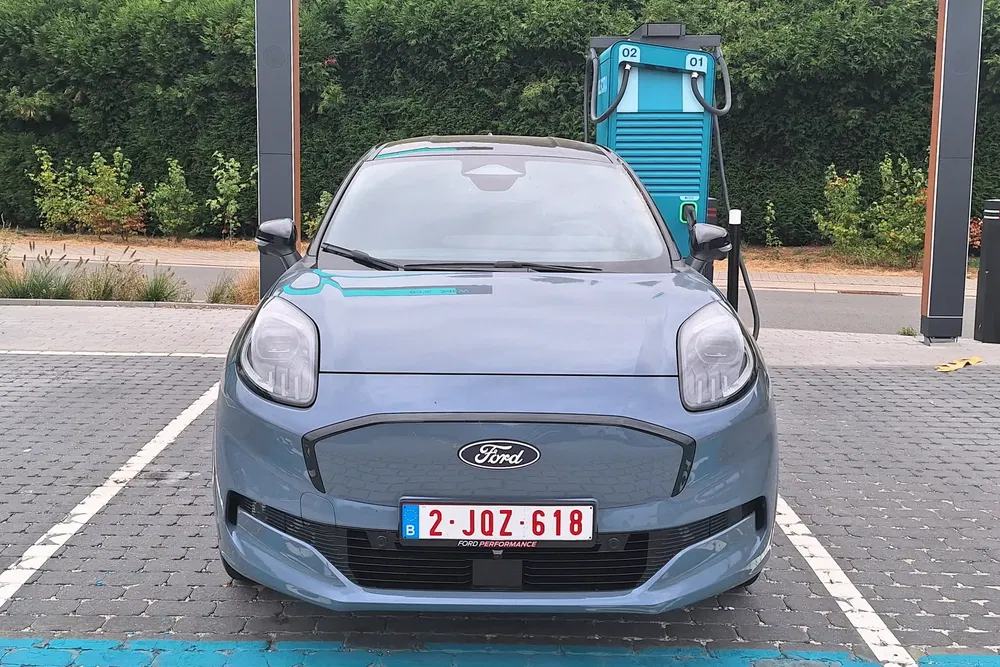 Voiture Ford électrique en charge à une station moderne, stationnement sur revêtement pavé.