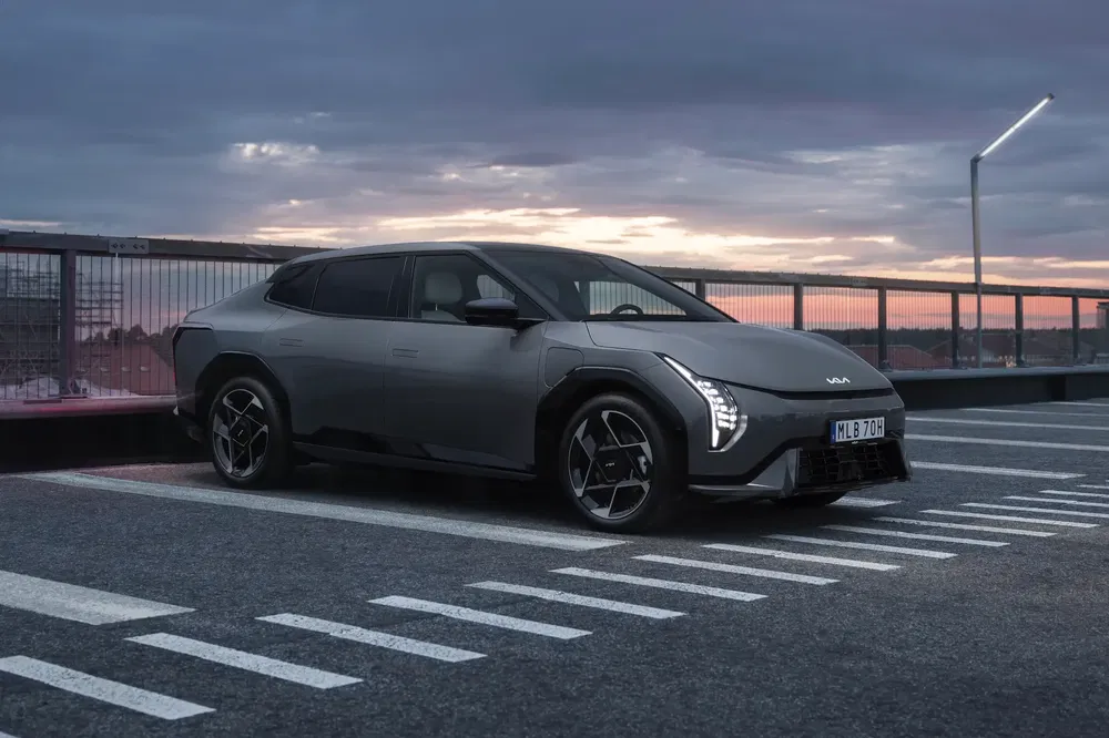 Grijze Kia EV9 geparkeerd op een dak bij schemering, benadrukt futuristisch design.