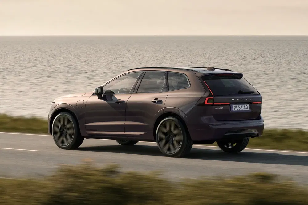 SUV Volvo XC60 roulant le long de la côte, océan en arrière-plan, ciel clair.