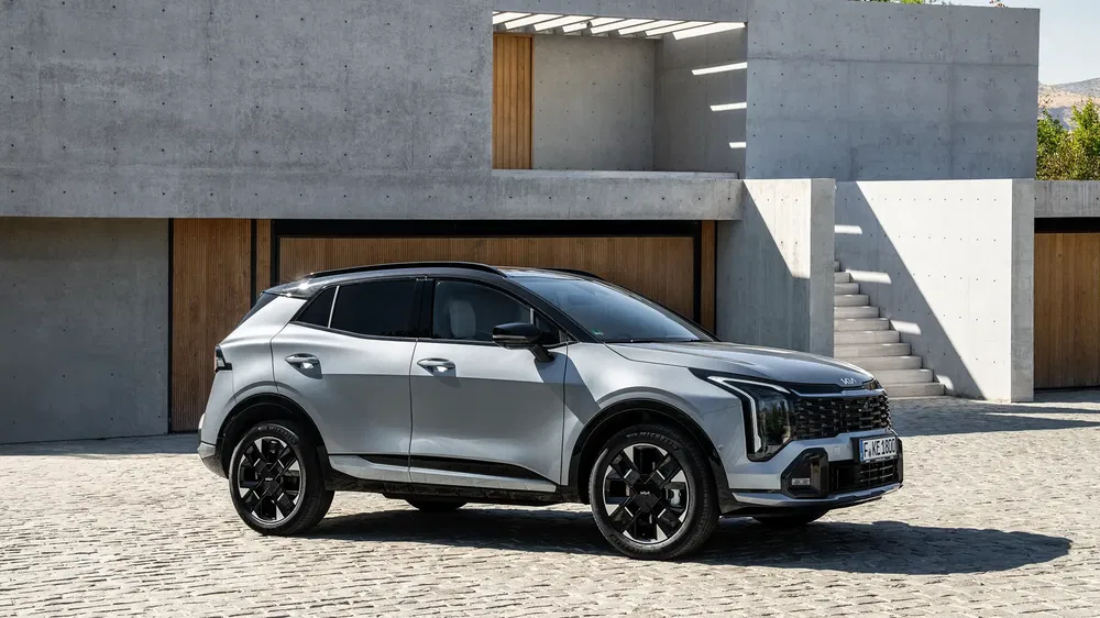 SUV Kia Sportage argenté garé devant une maison moderne en béton.