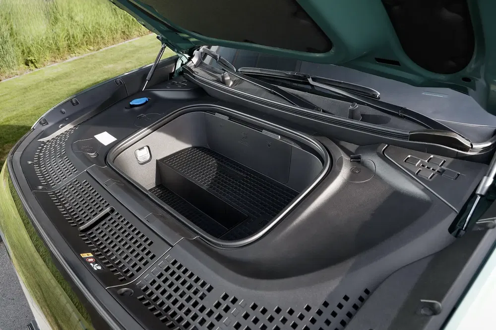 Coffre avant d'une Rivian R1T sous un capot de couleur verte en pleine nature.