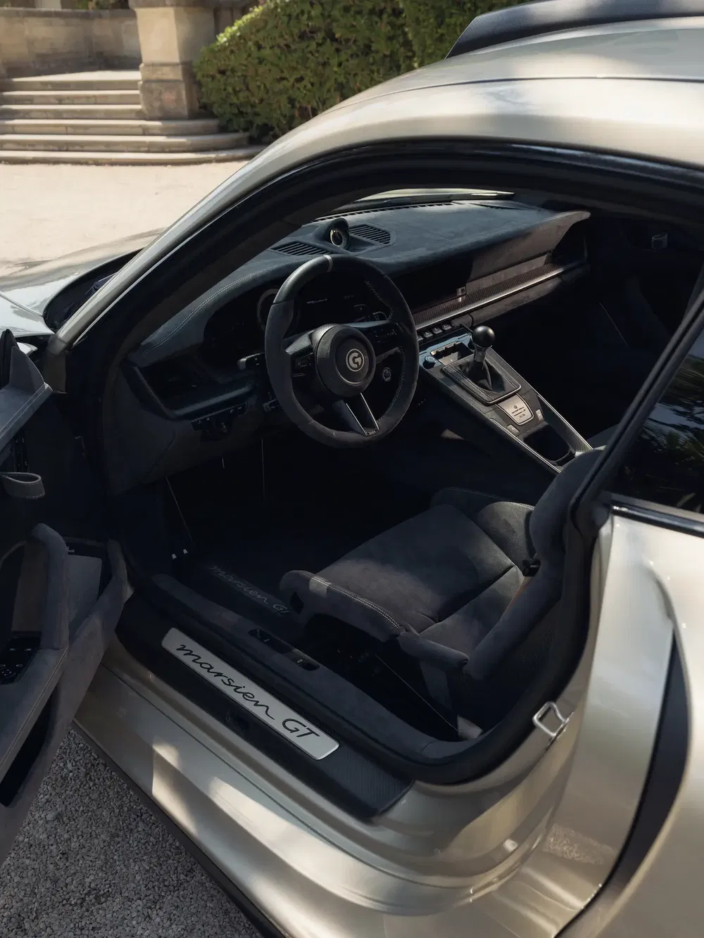 Vue intérieure d'une voiture de sport Marsien GT avec volant central et sièges en cuir.