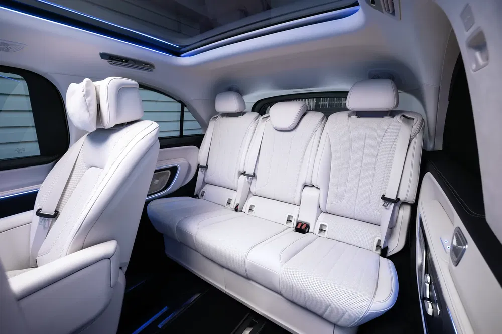 Ruim en luxueus interieur van een elektrische auto met witte lederen stoelen en panoramadak.