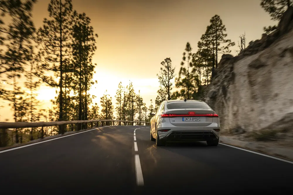 Audi A7 roulant au coucher du soleil sur une route de montagne sinueuse.