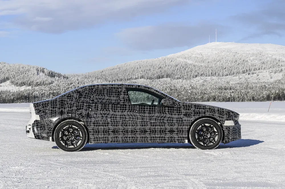 Voiture camouflée sur neige avec montagnes en arrière-plan, test hivernal d'un modèle mystérieux.