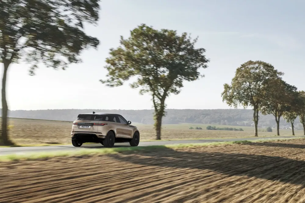 Range Rover Evoque roulant sur route de campagne entourée d'arbres et de champs.