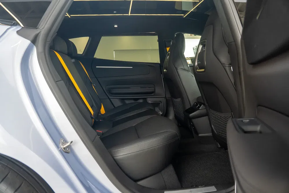 Intérieur de SUV Polestar avec sièges arrière en cuir noir et accents jaunes.