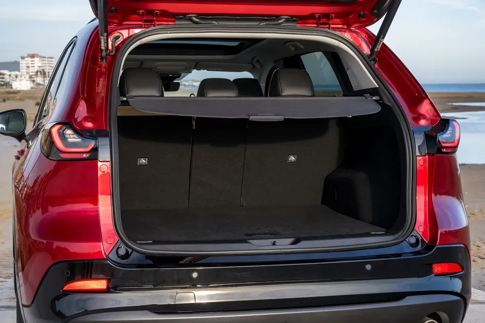 Ruime kofferbak van een rode SUV aan zee, open voor makkelijke belading.