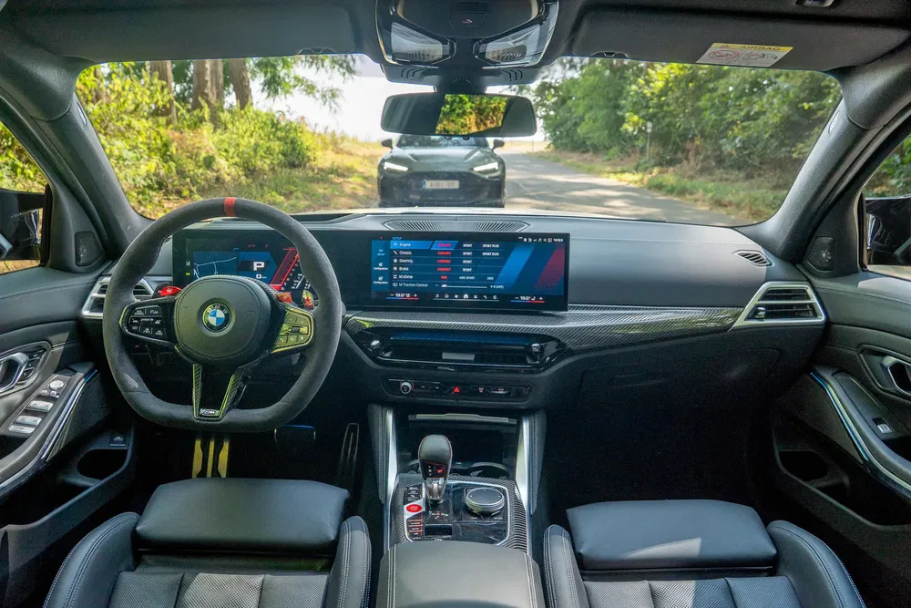 Interieur van een moderne BMW met groot digitaal scherm en carbonfiber afwerking.