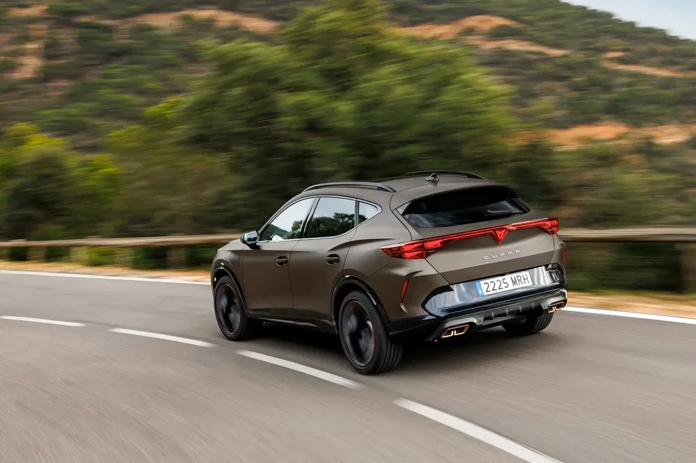 Cupra Formentor SUV op kronkelende weg, dynamische achterkant, sportief ontwerp.
