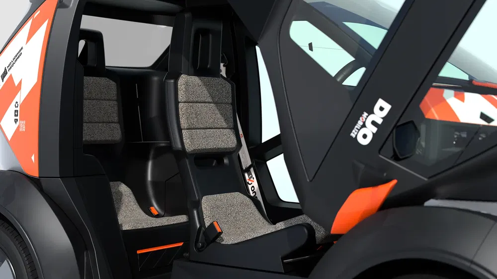 Intérieur de la Citroën Ami avec sièges en textile gris et accents orange.