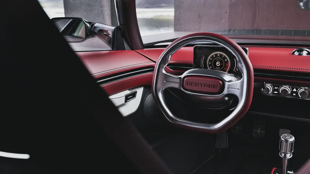 Bertone-auto-interieur met modern dashboard en rood lederen stuurwiel.