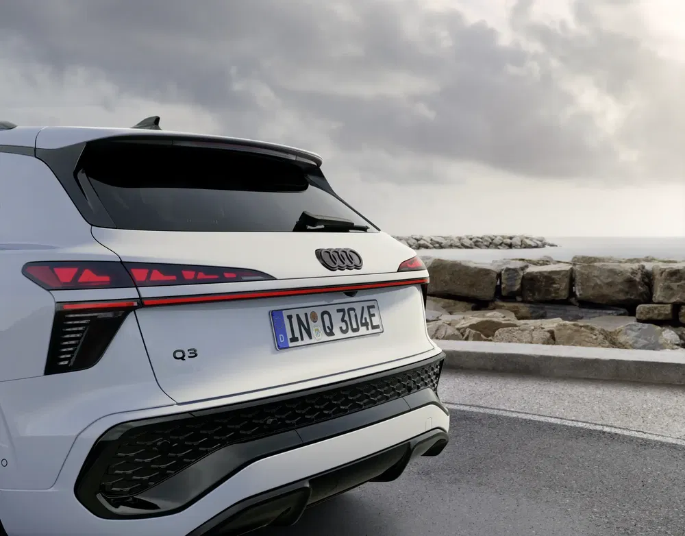 L'arrière de l'Audi Q3 blanc, stationné près d'un rivage rocheux par temps nuageux.