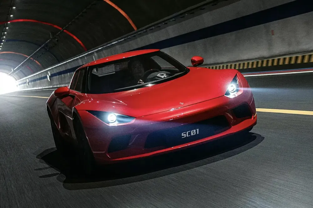 Voiture de sport rouge SC01 dans un tunnel, phares allumés, roulant vers la lumière.