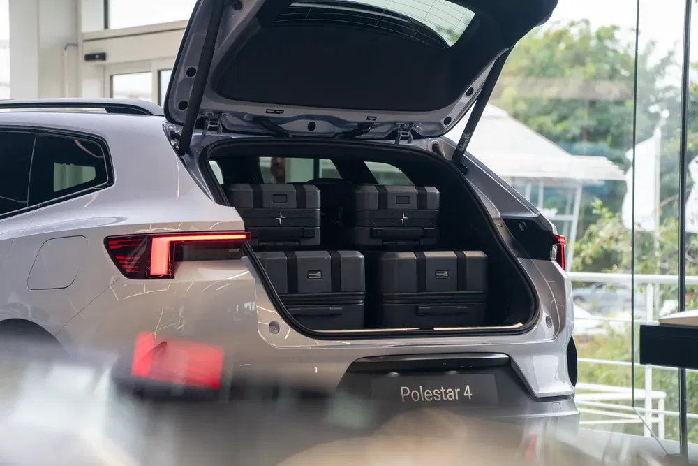 Coffre du Polestar 4 ouvert, avec valises noires empilées à l'intérieur, dans une concession.