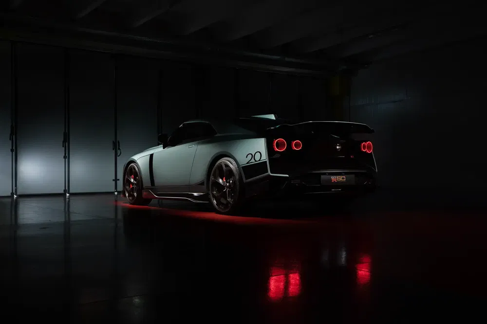 Nissan GT-R 50e anniversaire sous faible éclairage, lumières arrière rouges distinctives.