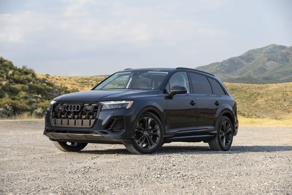 Audi Q7 noire garée sur terrain rocheux avec montagnes en arrière-plan.