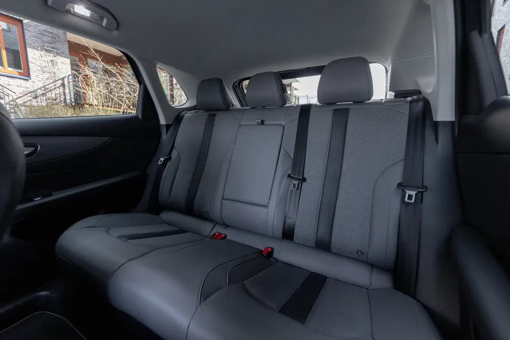 Intérieur spacieux d'une voiture moderne avec sièges arrière en tissu gris.