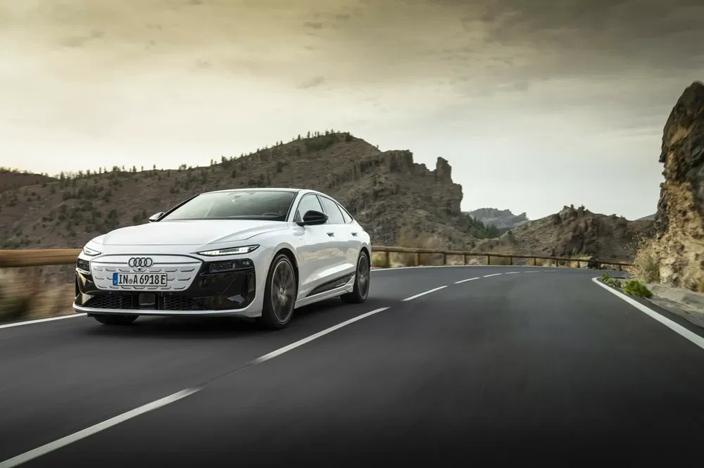 Audi A7 blanche sur route sinueuse avec paysage rocheux en arrière-plan.