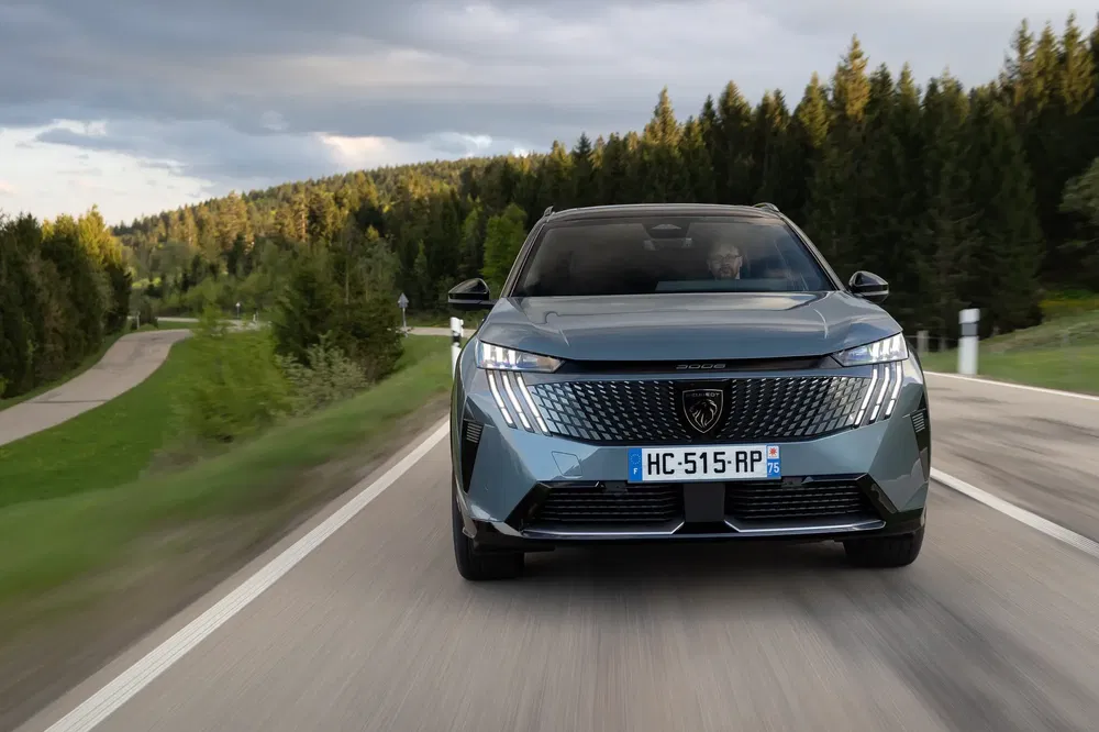 Peugeot 3008 roulant sur route sinueuse en milieu forestier, design moderne et élégant.