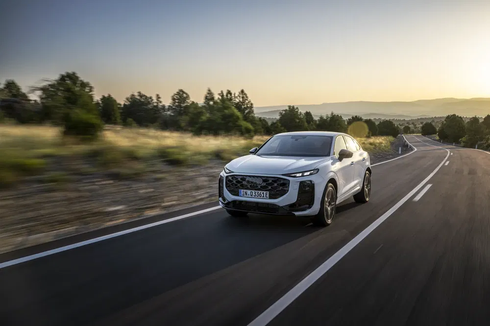SUV Audi roulant sur route dégagée avec coucher de soleil en arrière-plan.