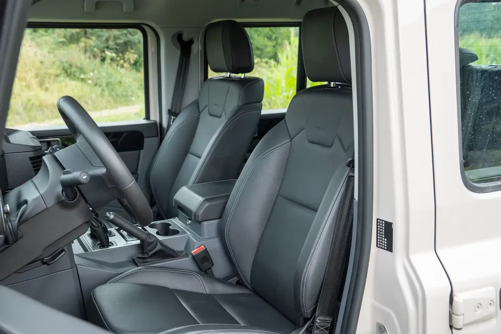 Interieur van de Ineos Grenadier met zwarte lederen stoelen en modern dashboard.