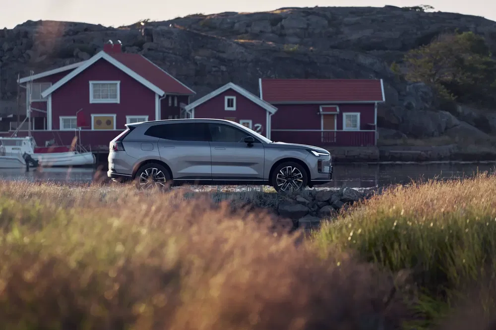 SUV argenté moderne près de maisons rouges sur un paysage côtier pittoresque.