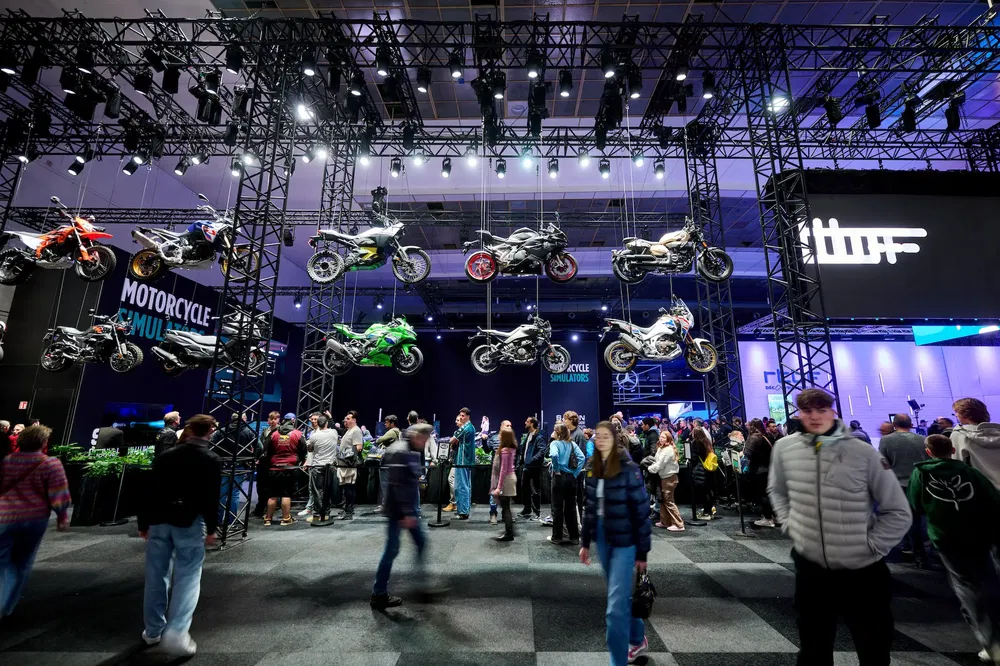 {"fr":"Exposition de moto avec plusieurs modèles suspendus, foule intéressée lors d'un salon automobile.","nl":"Motorexpositie met diverse modellen opgehangen, geïnteresseerde menigte op een autosalon."}