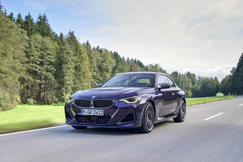 {"fr":"BMW Série 2 Coupé roulant sur une route bordée de forêts verdoyantes.","nl":"BMW 2-serie Coupé rijdt op een weg omringd door groene bossen."}