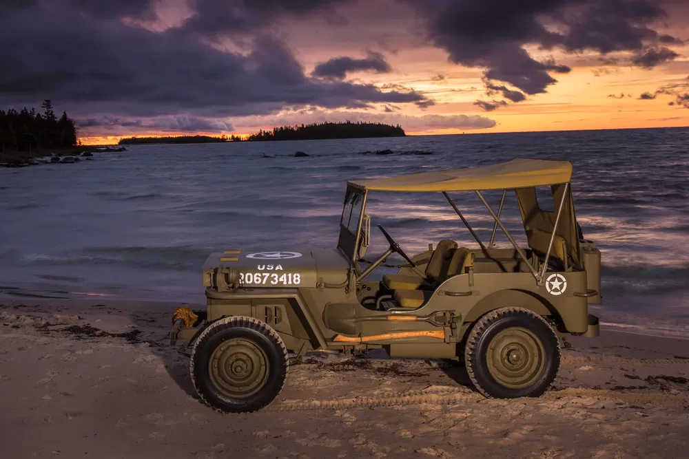 Militaire jeep op strand bij zonsondergang, dramatische oceaanhorizon.