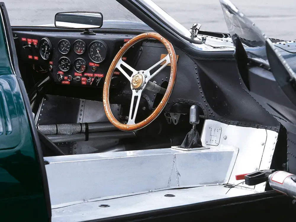 Intérieur d'une voiture de course classique avec volant en bois et tableau de bord analogique.