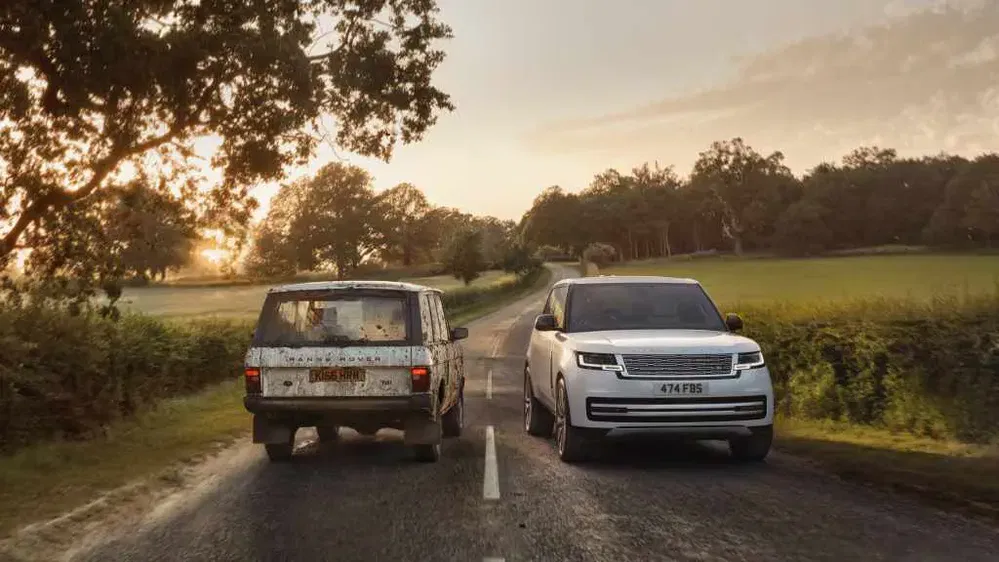 Deux Range Rovers sur une route de campagne, l'un moderne et l'autre classique.