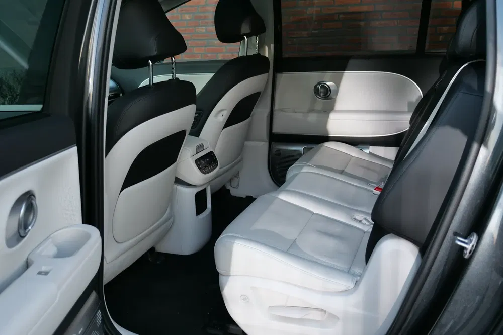 Intérieur spacieux d'une voiture avec sièges arrière en cuir blanc et accoudoirs élégants.