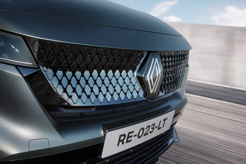 Calandre moderne Renault avec motif polygonal sur route, plaque RE-023-LT visible.