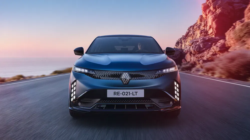 Elektrische Renault Mégane E-Tech op kustweg bij zonsondergang.