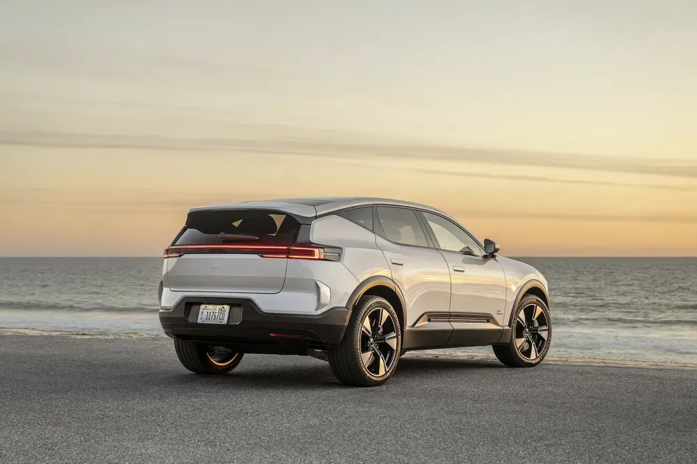 Vue arrière du SUV électrique Polestar 3 au bord de la mer au coucher du soleil.