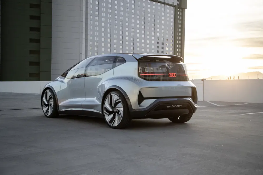 Zilveren Audi e-tron conceptauto bij zonsondergang op een stedelijke parkeerplaats.