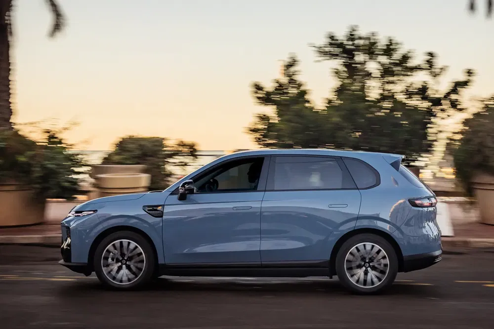 SUV électrique compact VinFast VF e35 bleu clair sur route côtière au coucher du soleil.