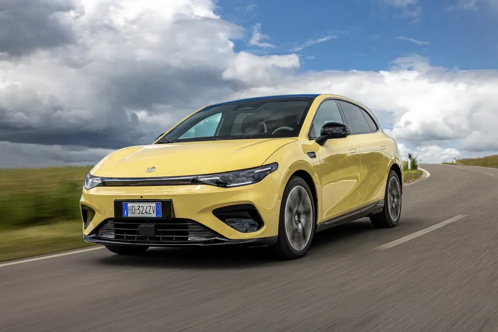 Voiture électrique MG sur une route de campagne, ciel nuageux en arrière-plan.